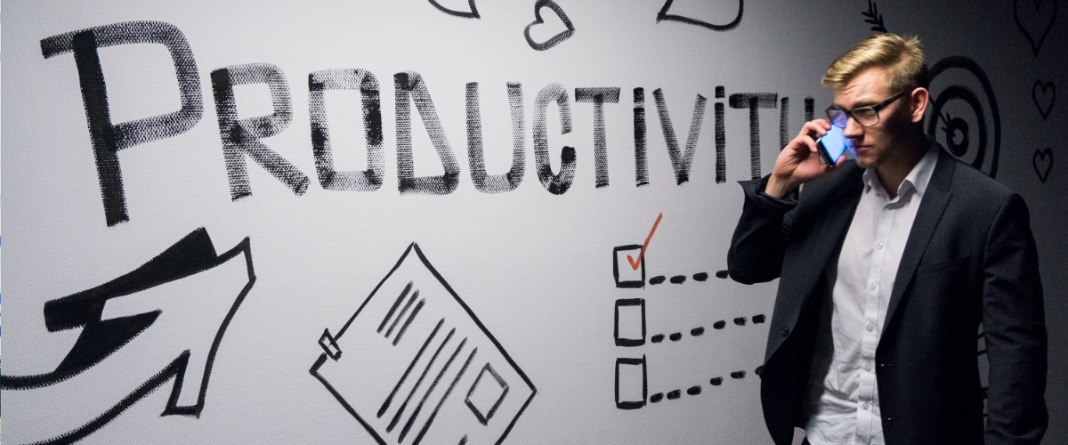 A man walking in front of a white board that says PRODUCTIVITY